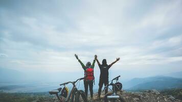 Asian lover woman and man Travel Nature. Travel relax ride a bike Wilderness in the wild. Standing on a rocky cliff. Thailand photo