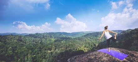 las mujeres asiáticas se relajan en las vacaciones. jugar si yoga. en el acantilado de roca de montaña. naturaleza de los bosques de montaña en tailandia foto