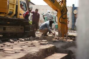 Magelang, Indonesia.09-17-2023.an excavator is dismantling and making a drainage hole photo