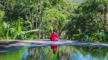 Young woman travel nature she standing exercise at the pool relaxing, Reflections of Asian woman on the water surface. photo