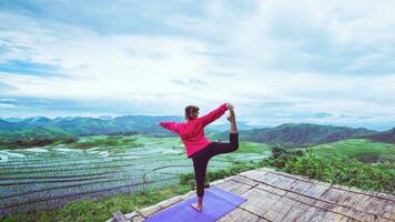 Asian woman relax in the holiday. Play if yoga. On the balcony landscape Natural Field. papongpieng in Thailand. photo