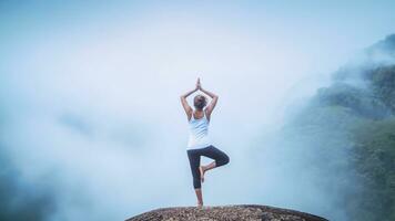 Asian woman relax in the holiday. Play if yoga. On the Moutain rock cliff photo