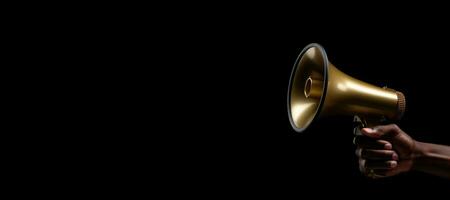 Generative AI, golden megaphone in hand on a empty black background, panoramic image with copy space photo