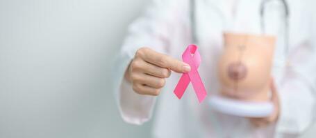 Pink October Breast Cancer Awareness month, doctor woman with pink Ribbon and Breast Anatomy model. National cancer survivors month, health diagnosis, Mother and World cancer day concept photo