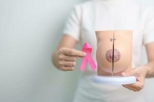 Pink October Breast Cancer Awareness month, woman with pink Ribbon and Breast Anatomy model. National cancer survivors month, health diagnosis, Mother and World cancer day concept photo