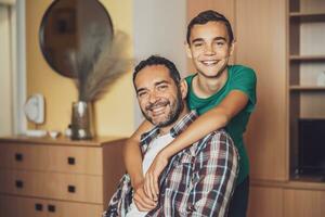 Portrait of happy father and son at home. They are embracing. photo