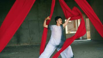 un asiático hombre jugando y colgando desde un rojo cuerda con un alegre cara video