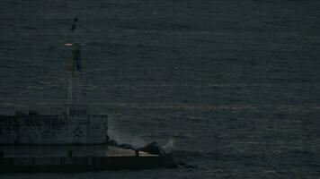 In Nea Kallikratia, Greece in night sea is lighthouse and burns the bulb video