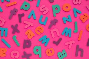 Color alphabet letters on pink background. World Dyslexia Day concept. Solving the educational problem of reading. Medical and mental health awareness. Logopedy, psychology, learning lessons photo