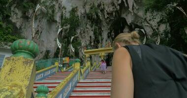 Young woman at Batu Caves, Malaysia climbs the stairs and takes pictures on tablet video