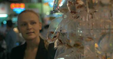 Young blond woman take a picture of gold aquarium fishes packed in plastic bag Hong Kong, China video