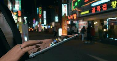 Woman browsing in web on pad in night Seoul, South Korea video