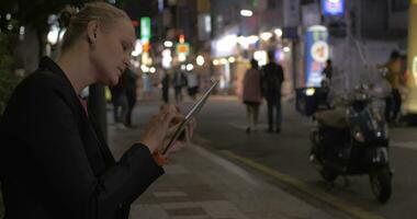 Woman working with pad in night Seoul street, South Korea video