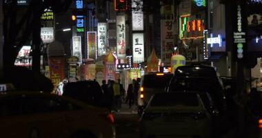 Street with illuminated banners, people and cars in night Seoul, South Korea video