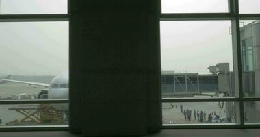 Unloading the plane with attached air bridge, view from the window video