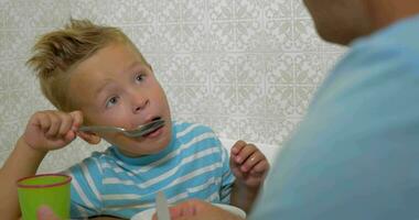 Father teaching son to use a spoon during eating video