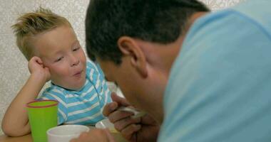 Son speaking with father and eat using a spoon and smiling video