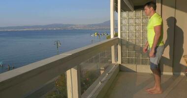 Man beginning push ups on the balcony with sea view background video