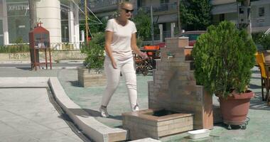 On street in city of Perea, Greece young girl comes to the faucet and washes her hands video