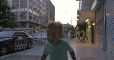 Little boy runs along a busy street of Thessaloniki, Greece video