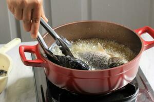 Process of Frying River Carp Fish in a Red Frying Pan. photo