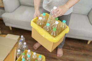 Home recycle eco green zero concept Man throwing empty plastic bottle in recycling bin with yellow garbage bags at home photo