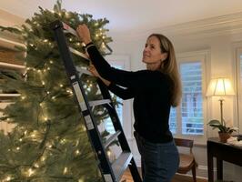 Woman decorating a Christmas tree with ornaments and lights AI Generative photo