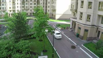 Two cars driving in the yard of multistorey houses, aerial view video