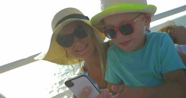 Young woman and son are watching something in smartphone in riding motor boat video