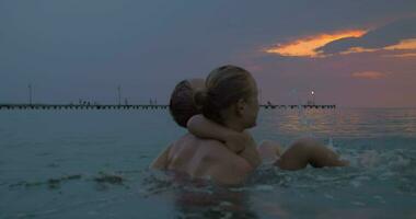 a tramonto madre con figlio nuoto nel mare di città Perea, Grecia video