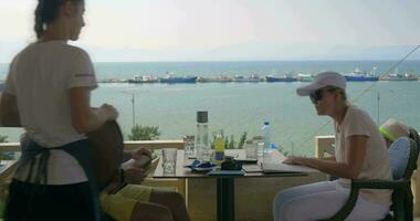 Young couple sitting in a cafe, the waitress takes the order from the woman, the man studying the menu video