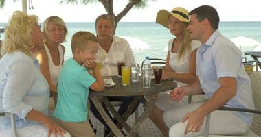 Big family sitting at table on the sea coast in city of Perea, Greece video