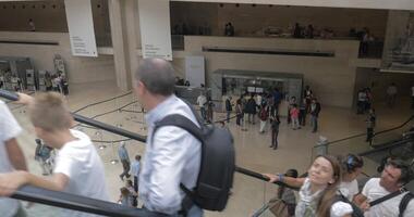 People riding escalators in the Louvre hall video