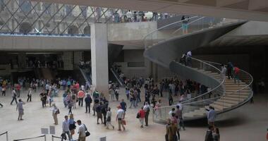 Crowded hall with spiral stairs in Louvre Pyramid video