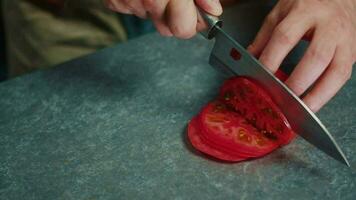 el cocinar usos un agudo cuchillo a cortar el Tomates dentro Delgado rebanadas video