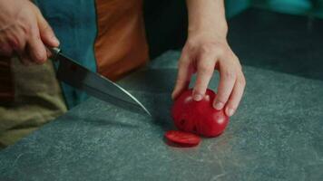 The cook slices the tomatoes with a sharp knife. Side view video