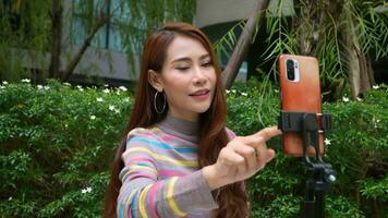 Beautiful Asian woman female blogger use smartphone for broadcasts live on social networks, speaks via video calling on a mobile phone, content creator, influencer and communication concept.