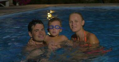 contento famiglia con bambino nel il piscina a notte video