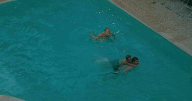 padres y niño nadando en el piscina video