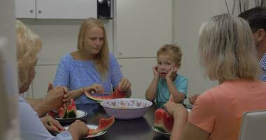 família com criança comendo Melancia dentro a cozinha video