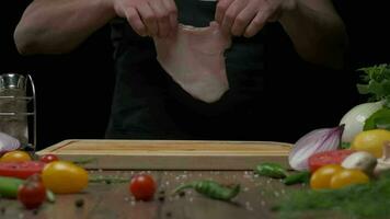 Professional chef salting chicken fillet steak, close up slow motion video