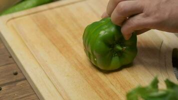 Professional chef prepares and cuts green bell pepper. Close up slow motion video