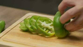 Professional chef prepares and cuts green bell pepper. Close up slow motion video