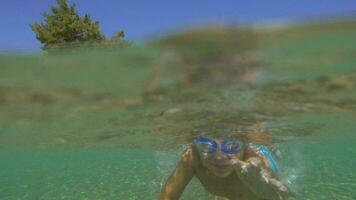 garçon dans des lunettes de protection nager en dessous de le mer l'eau video