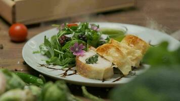 Chicken roll with spinach nicely served on a plate with greens, flower decorations and green oil video