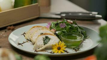 Chicken roll with spinach nicely served on a plate with greens, flower decorations and green oil video