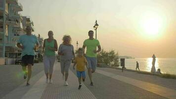 vänlig familj löpning till Avsluta på de trottoar på solnedgång video