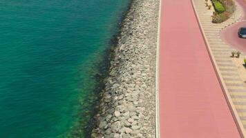 A drone flies over a road along the seashore near Dubai, United Arab Emirates. Aerial video