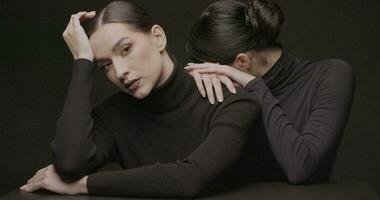 deux Jeune élégant femmes avec bien maquillage sur une noir Contexte. lent mouvement, studio tir. video