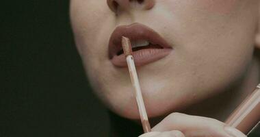 Young elegant woman applies gloss to her lips. Close Up, slow Motion, Studio Shot. video